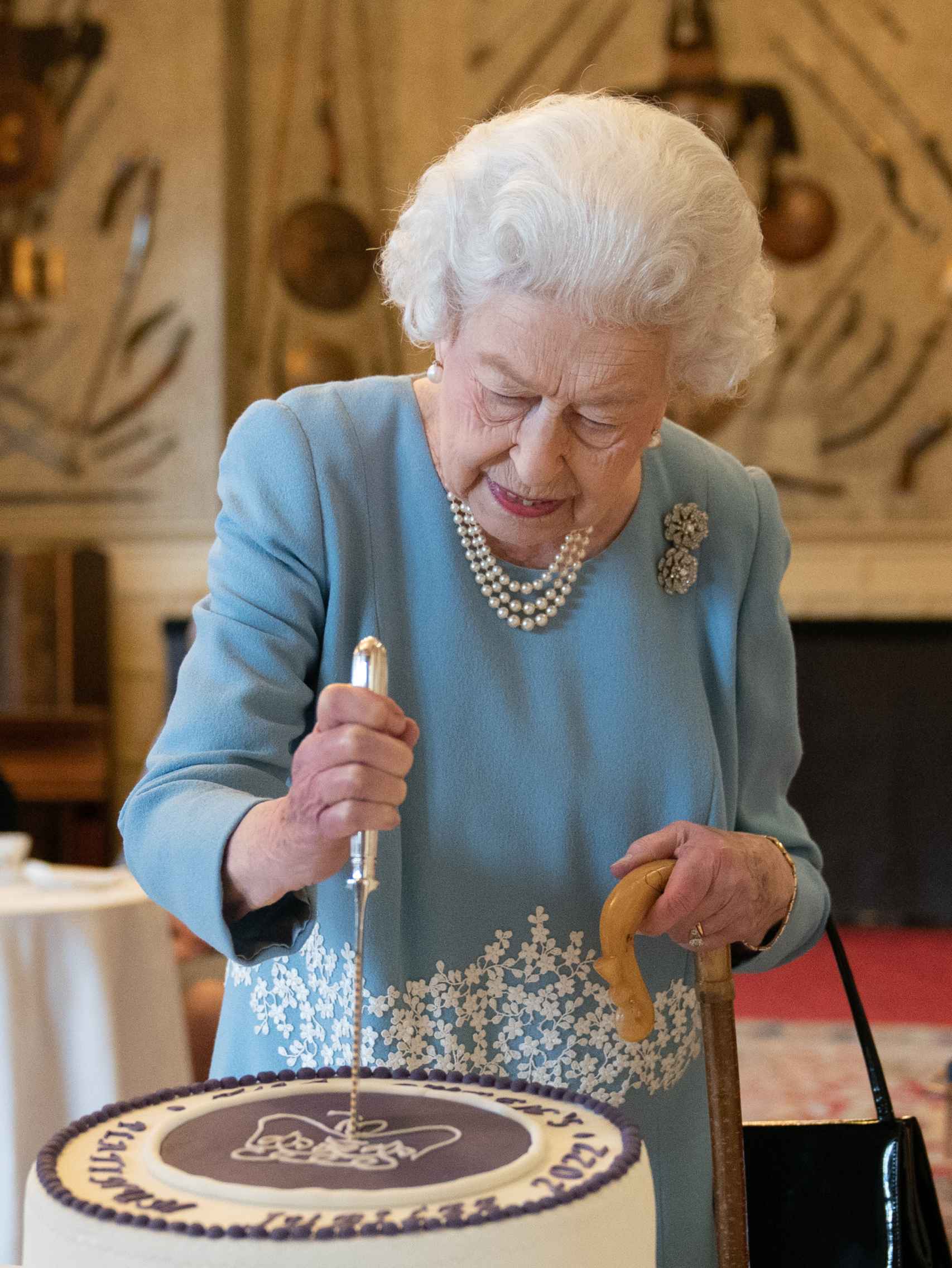 La reina cortando la tarta con el símbolo del jubileo.