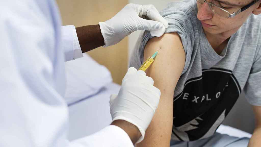 Personal sanitario vacuna a un joven.