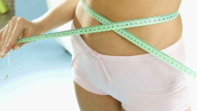 Una mujer mide el perímetro de su cintura.