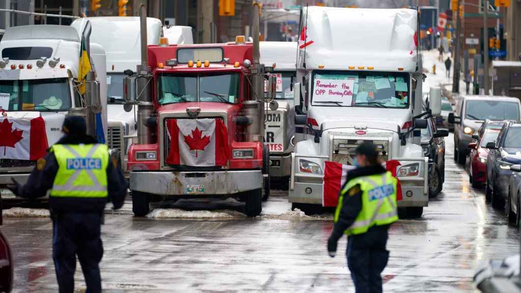Dos policías de Ottawa frente a camiones de manifestantes antivacunas.
