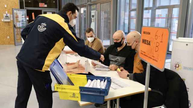 Un empleado entrega el voto por correo en una mesa electoral.