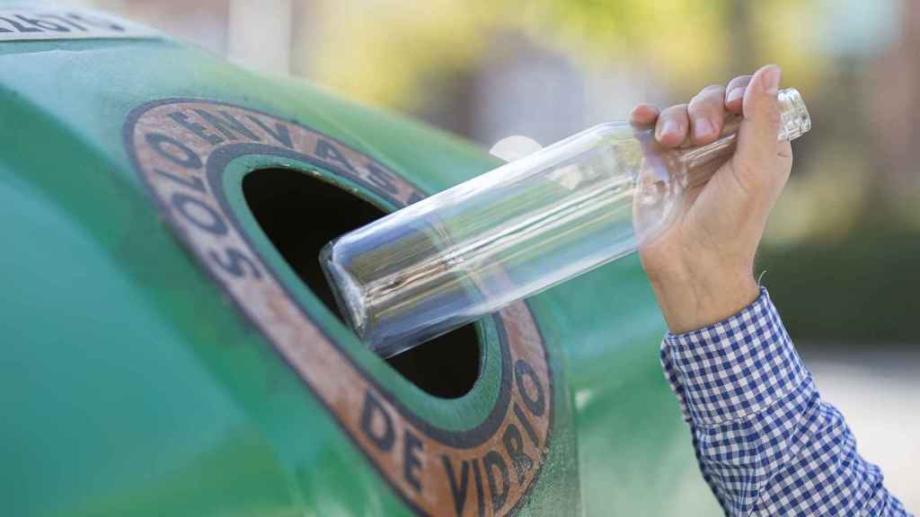 Una persona recicla en el contenedor de vidrio