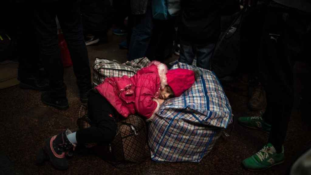 Una niña duerme en la estación central sobre las maletas, tras varios días de viaje.
