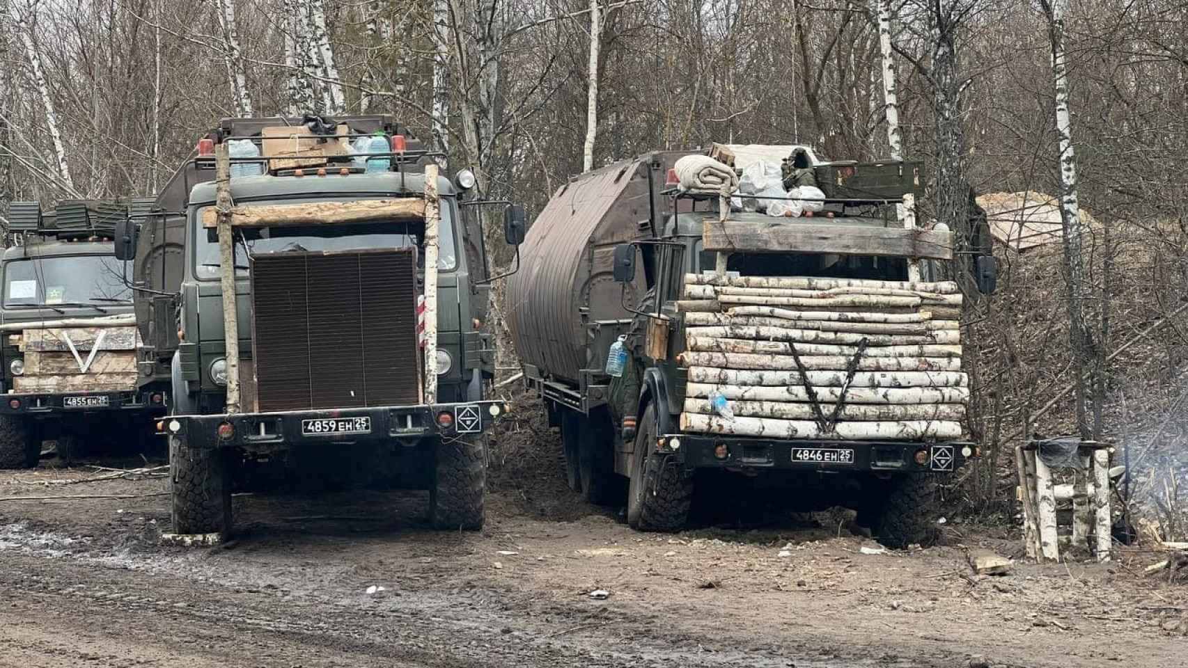 Camiones rusos con tablas de madera y estructuras en la cabina.