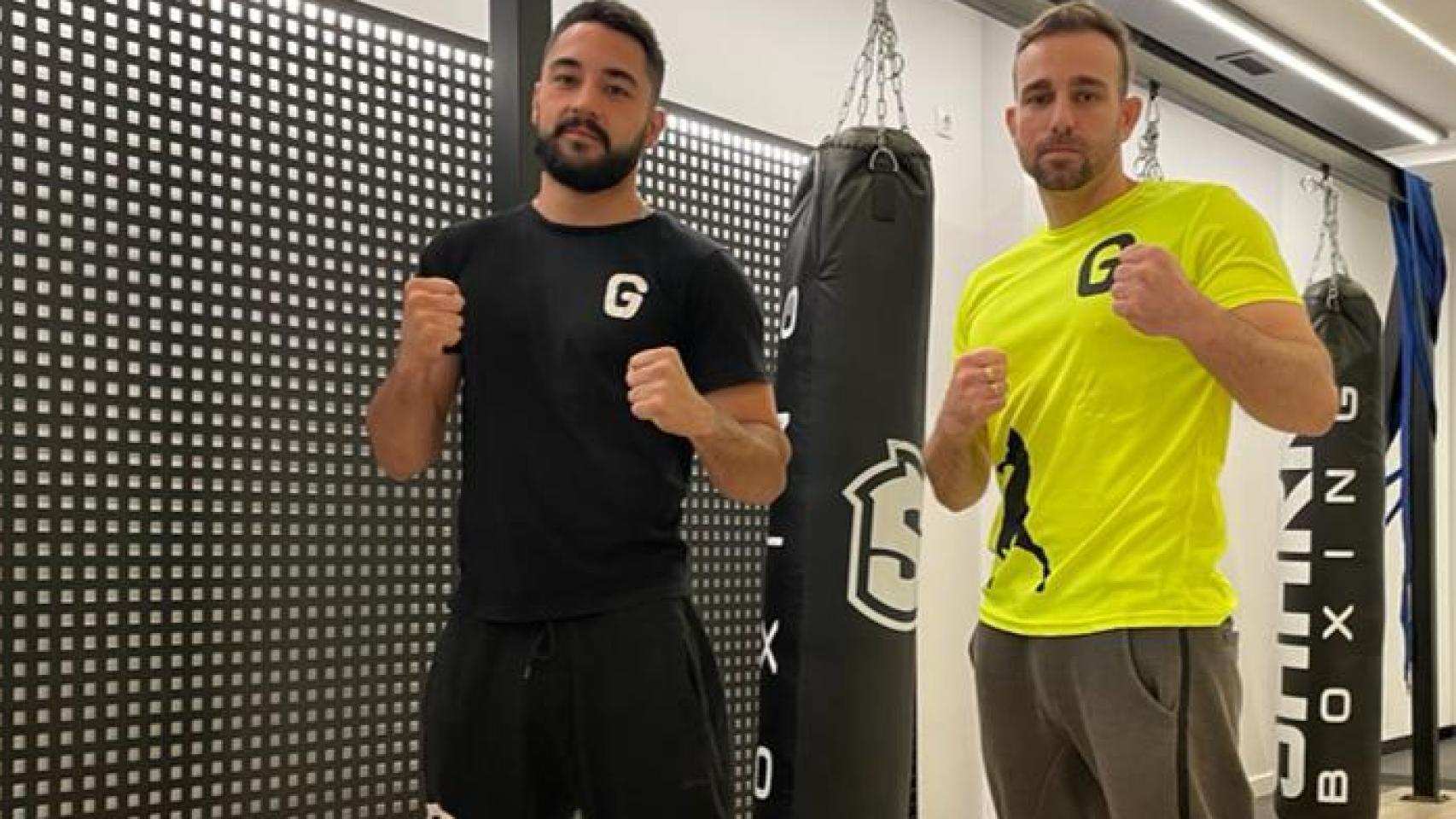 Un hombre en un ring de boxeo con un hombre con un pantalón corto blanco y  una camiseta que dice boxer.