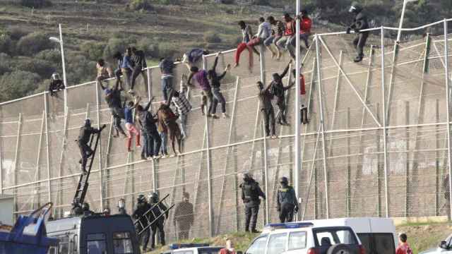 Unos 500 migrantes hacen el signo de la victoria tras saltar la valla de Melilla.