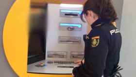 Una Policía Nacional revisa un cajero automático