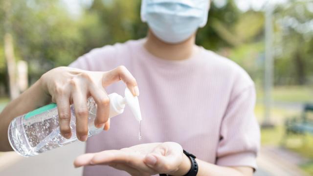 Imagen de archivo de una persona con mascarilla desinfectándose las manos.