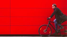 Un hombre monta en bicicleta frente a una pared roja