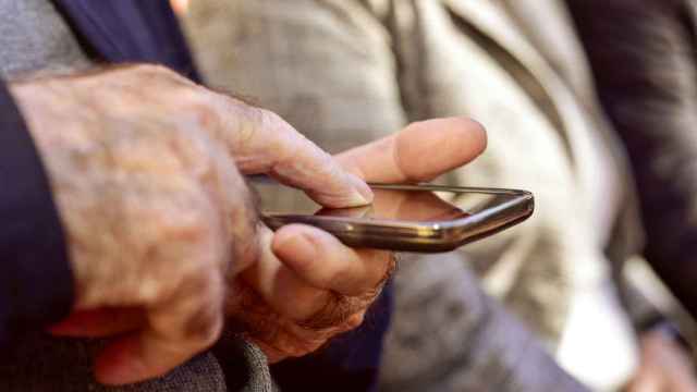 Un hombre anciano pulsa la pantalla de un teléfono móvil con su dedo