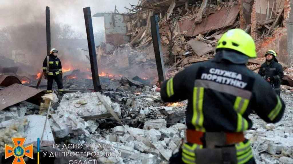 Bomberos trabajan entre los restos de los edificios dañados por un ataque aéreo en Dnipro.