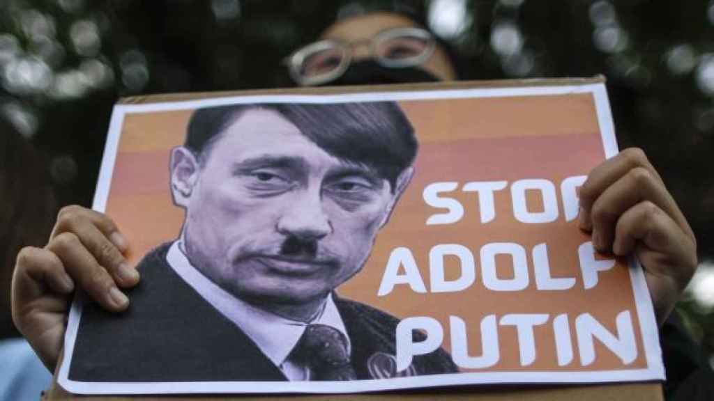 Un manifestante contra la invasión en Ucrania lleva un cartel de Putin disfrazado de Hitler.