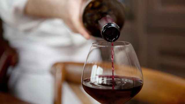 Un camarero sirve una copa de vino tinto.