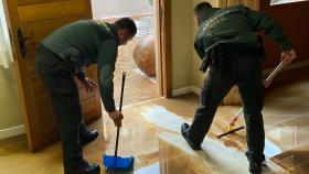 Dos guardias civiles achicando agua en la residencia.