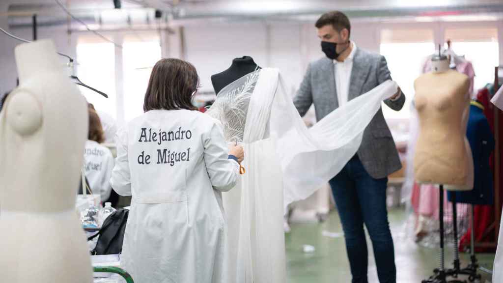 Alejandro de Miguel con una trabajadora arreglando un vestido.