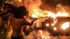 Un manifestante intenta apagar un fuego durante la manifestación en Lima. Efe