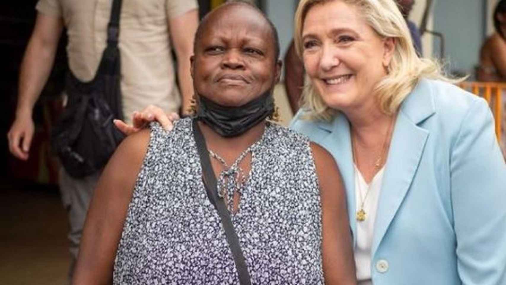 Imagen de campaña de Marine Le Pen que ha generado polémica porque sólo toca con un dedo a la votante francesa de origen africano.