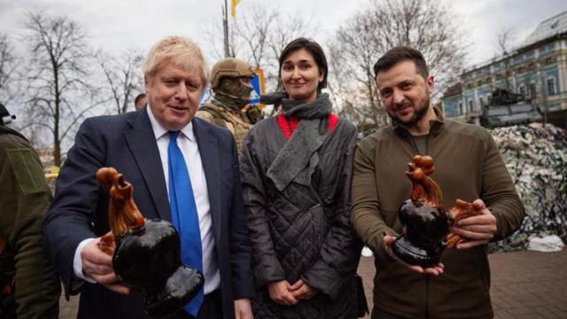 Boris Johnson y Volodimir Zelenski posan con la mujer que les ha regalado unos gallos de cerámica.