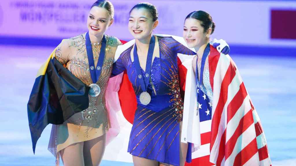 Alysa Liu, a la derecha, posando con su medalla de bronce y la bandera de Estados Unidos