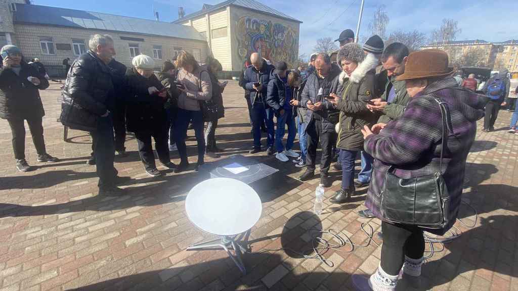 Ciudadanos ucranianos de Ivankiv reunidos alrededor de una antena Starlink.