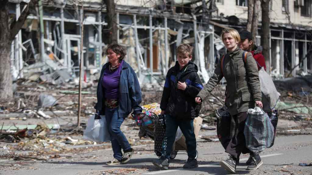 Ciudadanos ucranianos caminan con sus pertenencias en mano por las calles de la bombardeada Mariúpol.