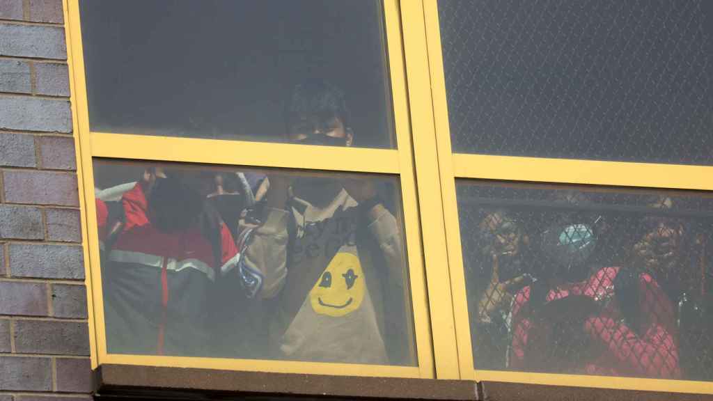 Niños de un colegio cercano se asoman a la ventana para ver lo ocurrido en la estación de Brooklyn.