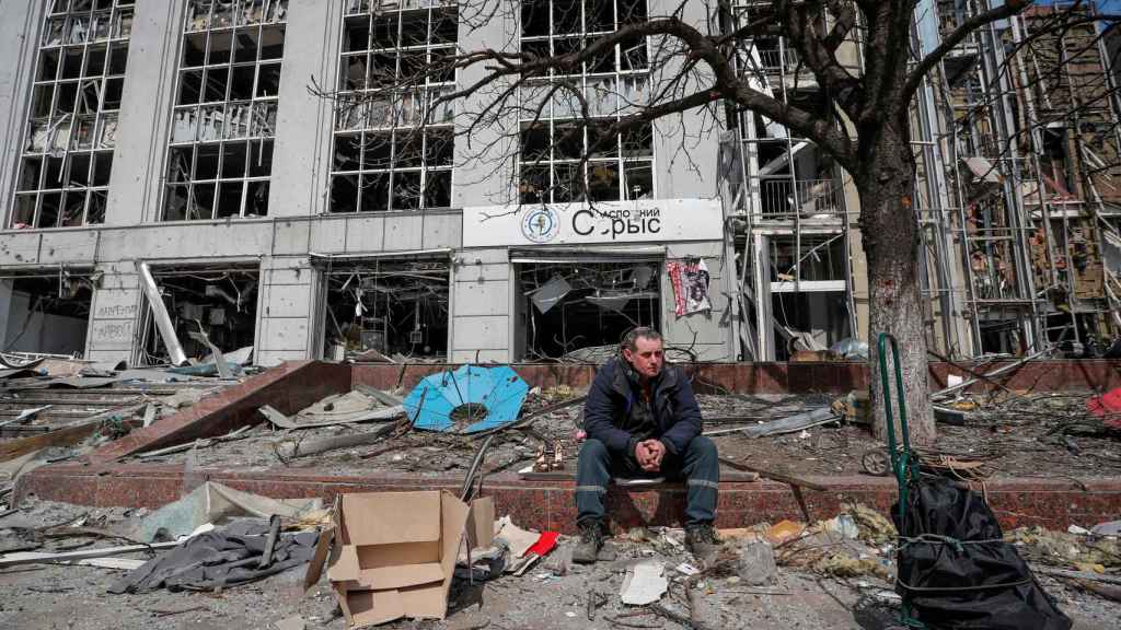 Un hombre sentado en los escombros de un edificio en Mariúpol.