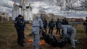 Personal forense trabaja en una fosa común tras la iglesia de St. Andrew Pervozvannoho, en Bucha (Ucrania).