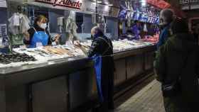 Dos vendedores charlan en un puesto de pescado y marisco en el Mercado Central de Valencia.