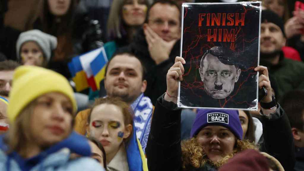 Una manifestante muestra una pancarta donde Putin aparece caracterizado como Hitler este martes en Varsovia.