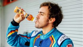 El piloto de Fórmula 1, Fernando Alonso, bebiendo la bebida de naranja y mango de Raw Super Drink.