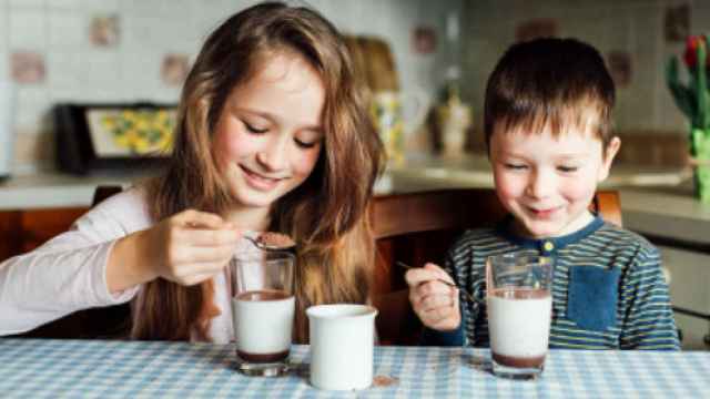 Dos niños tomando leche con cacao soluble.