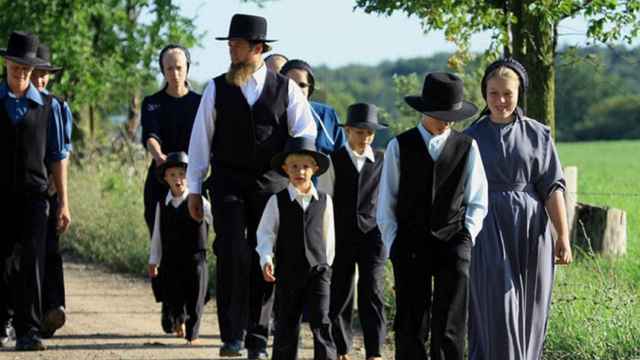 Una familia amish caminando por el campo.