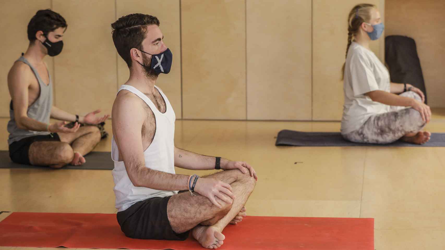 Varias personas realizan yoga en las instalaciones de un gimnasio.