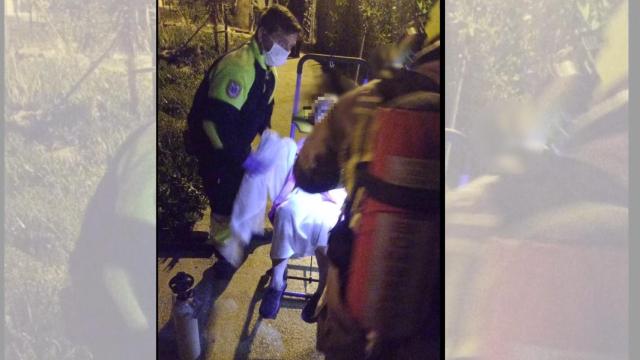 Los bomberos de Alicante sacan a un persona afectada por el humo de una vivienda.