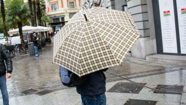 Un joven se protege de la lluvia con un paraguas.