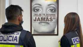 Dos agentes de la Policía Nacional, ante el cartel de una campaña contra la violencia machista.