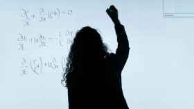 Una mujer escribe operaciones matemáticas en una pizarra.