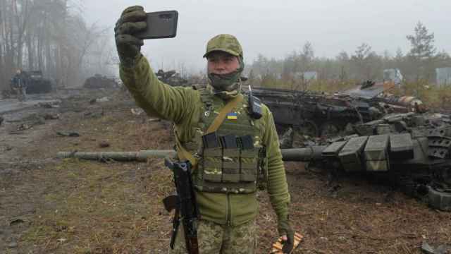Un soldado ucraniano se fotografía junto a un T-72 ruso destruido en Dmytrivka.