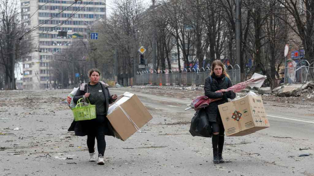 Dos mujeres llevan restos de sus pertenencias en Mariúpol.