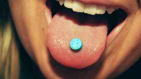 Una persona muestra una pastilla en su lengua durante una fiesta.
