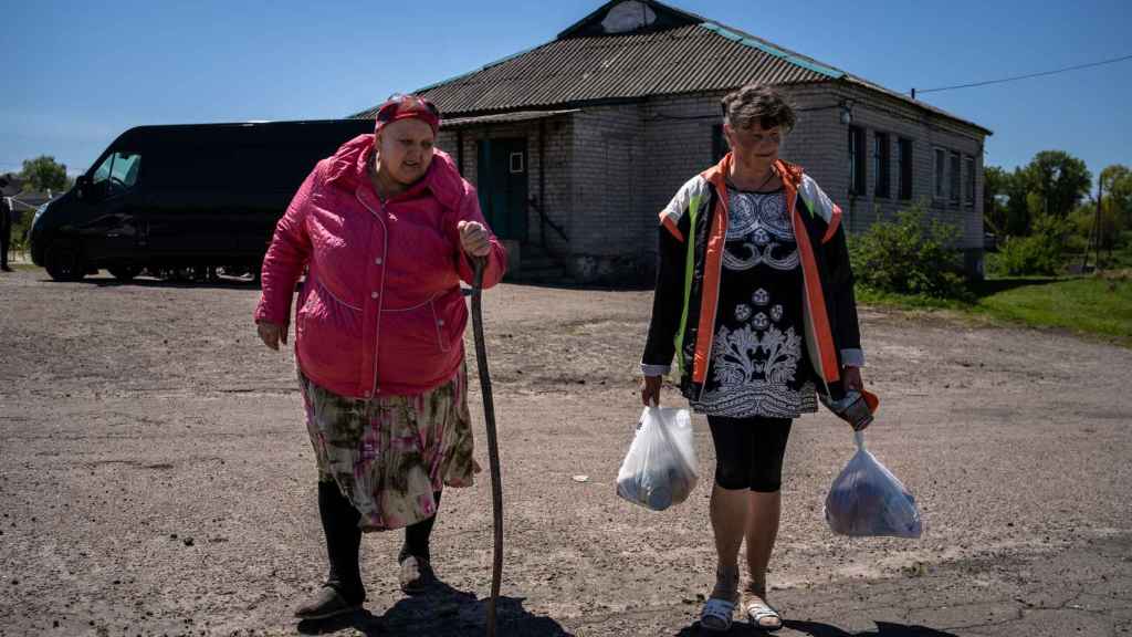 Dos mujeres regresan a sus casas tras acercarse a la entrada del pueblo a recoger la comida de la ONG de José Andrés.