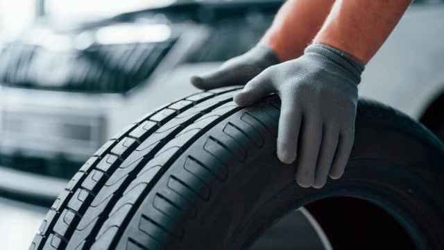 Un hombre sujetando un neumático.