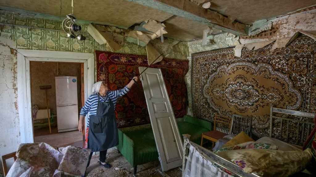 Una mujer ucraniana muestra su casa dañada durante la invasión rusa en el pueblo de Zahaltsi.