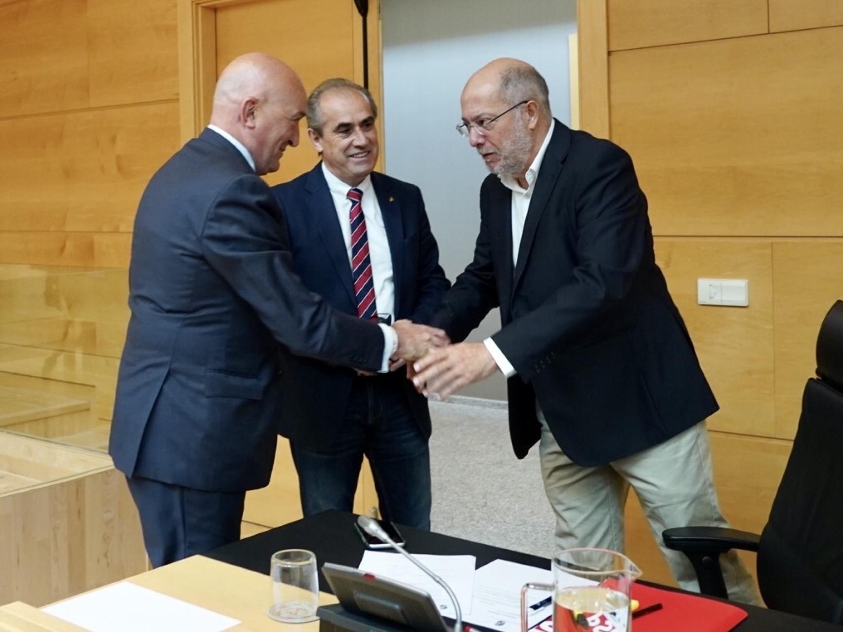 Los procuradores socialista y de Ciudadanos, Luis Briones y Francisco Igea, saludan al consejero de la Presidencia, Jesús Julio Carnero, antes de su comparecencia en las Cortes este lunes.