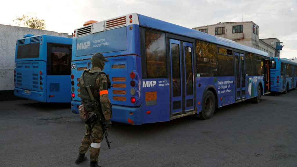 Un soldado prorruso custodia los autobuses en los que viajan los soldados ucranianos que se han rendido.