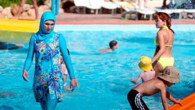 Una mujer con la prenda del burkini en una piscina.