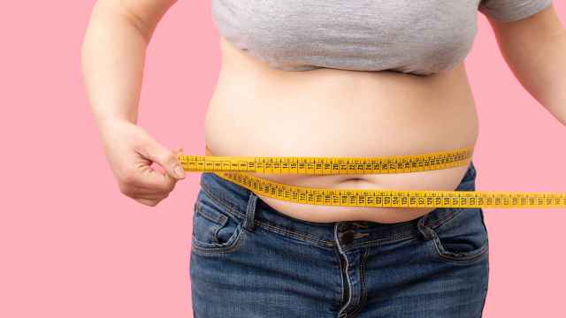 Una mujer con obesidad se mide la cintura.
