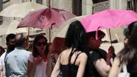 Varias personas se protegen con parasoles este viernes en Valencia.
