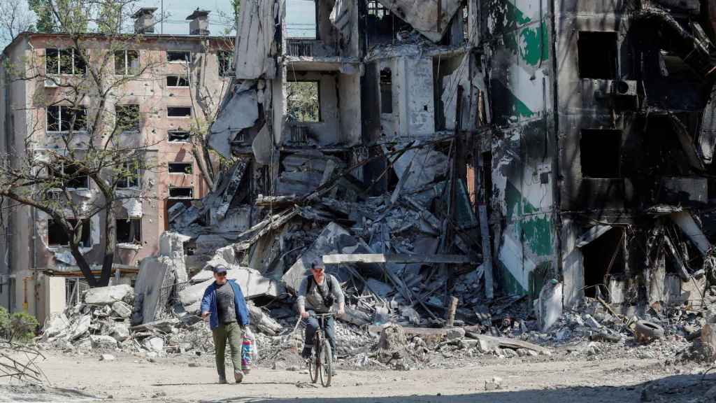 Dos personas pasan junto a un edificio bombardeado en Mariúpol.